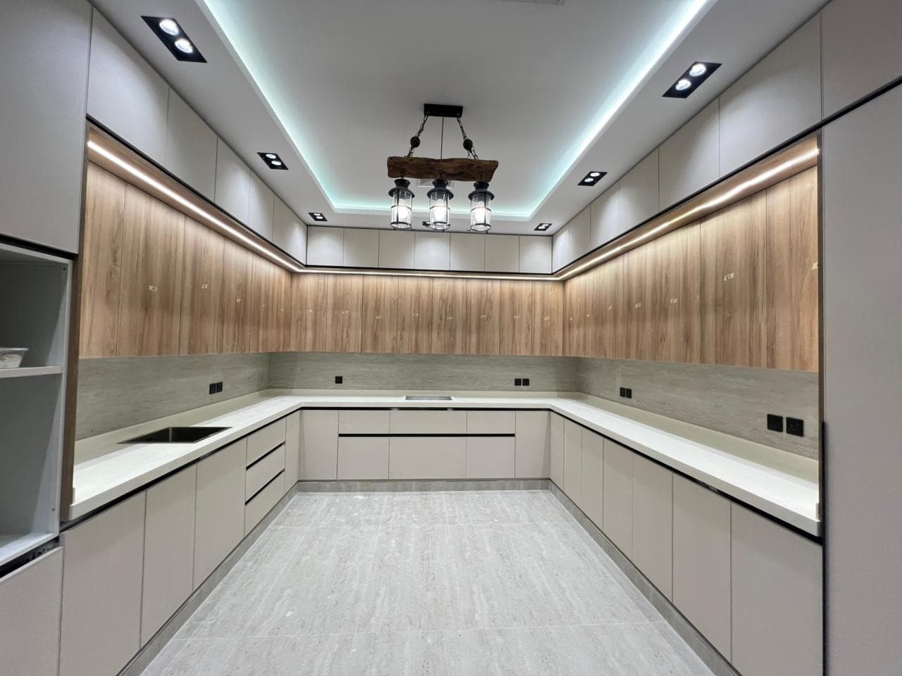Kitchen with wood-tone wall cabinets and grey base units — built by Blum for Kitchens